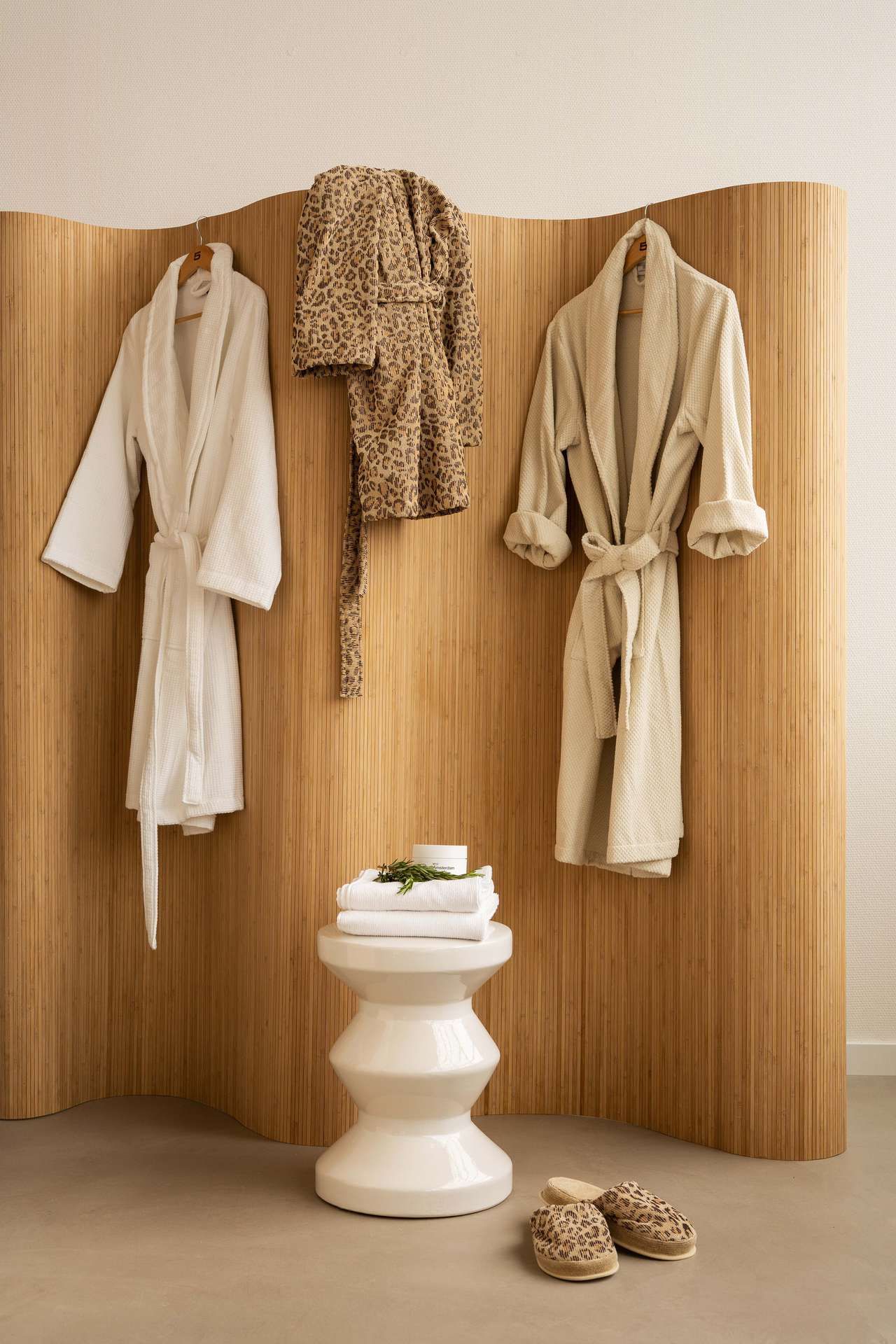 3 badjassen hangen aan houten roomdivider