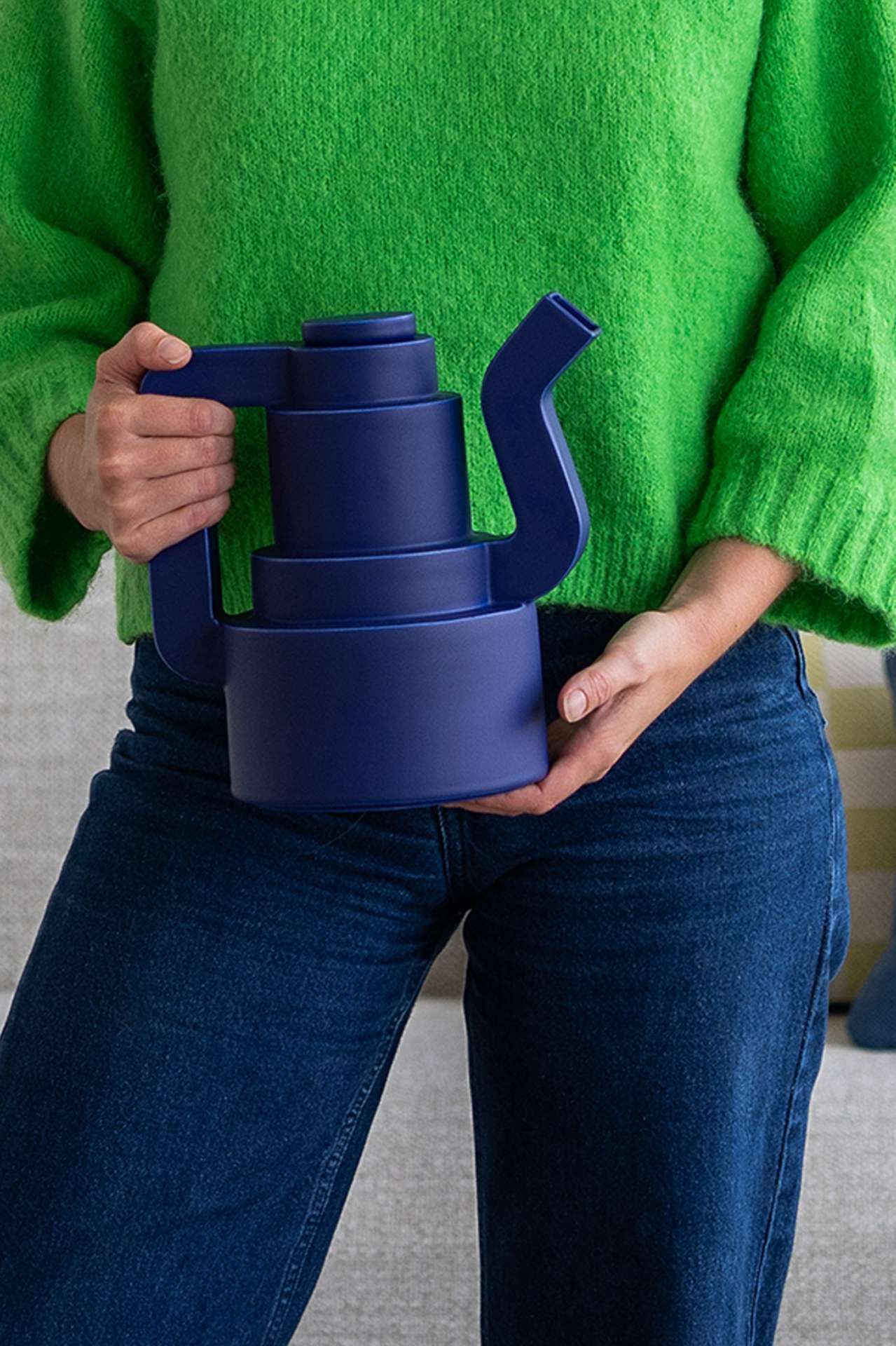 Donkerblauwe koffiekan wordt vastgehouden voor vrouw in groene trui