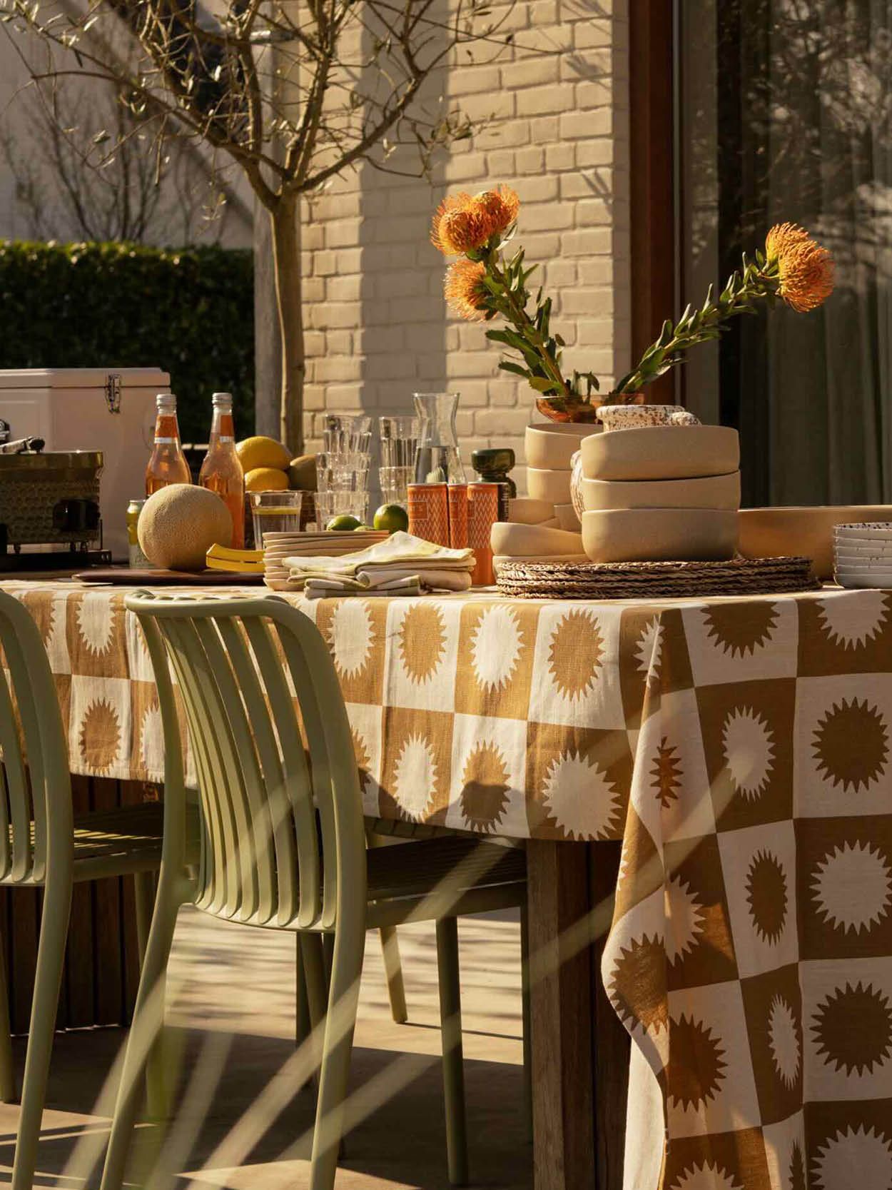 Gedekte tuintafel met geblokt tafelkleed en groene tuinstoelen