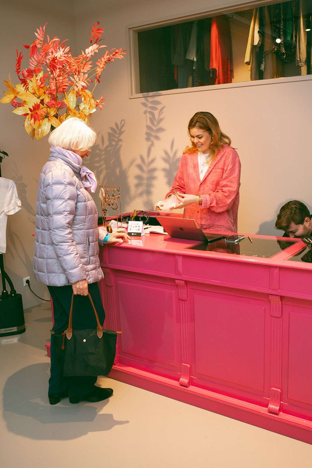 Eloise van oranje achter een roze toonbank met klant