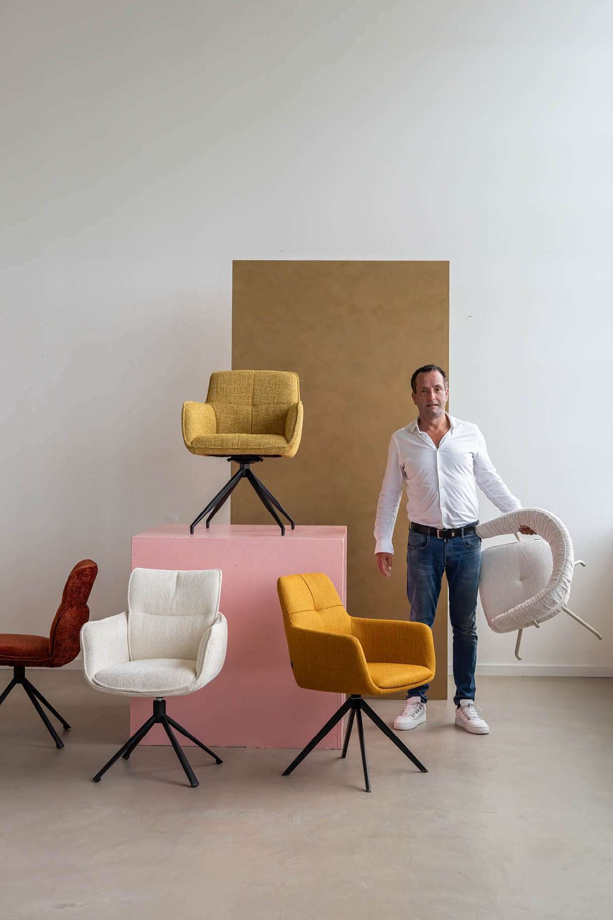 Man met stoel in zijn hand en verschillende stoelen er omheen