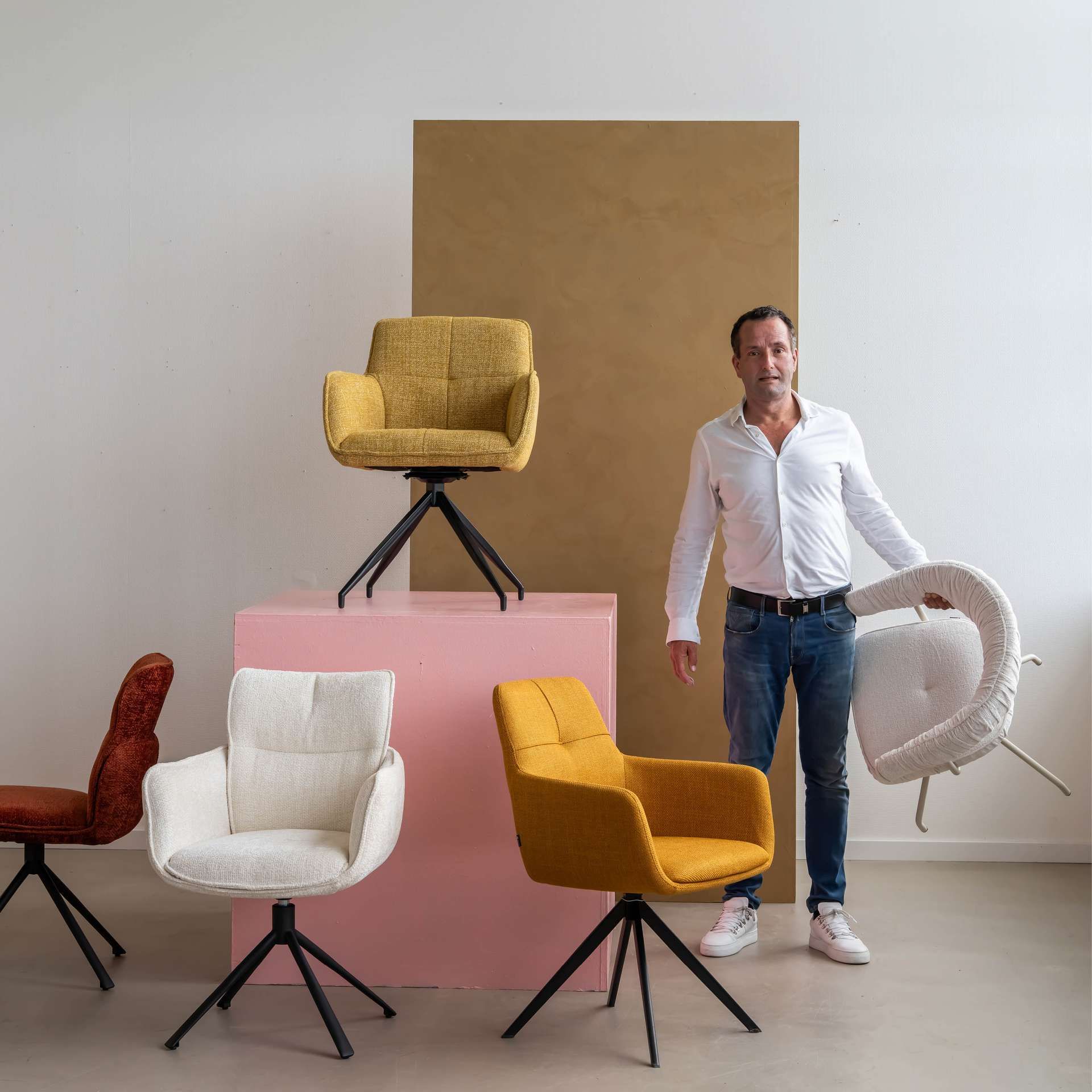 Man met stoel in zijn hand en verschillende stoelen er omheen