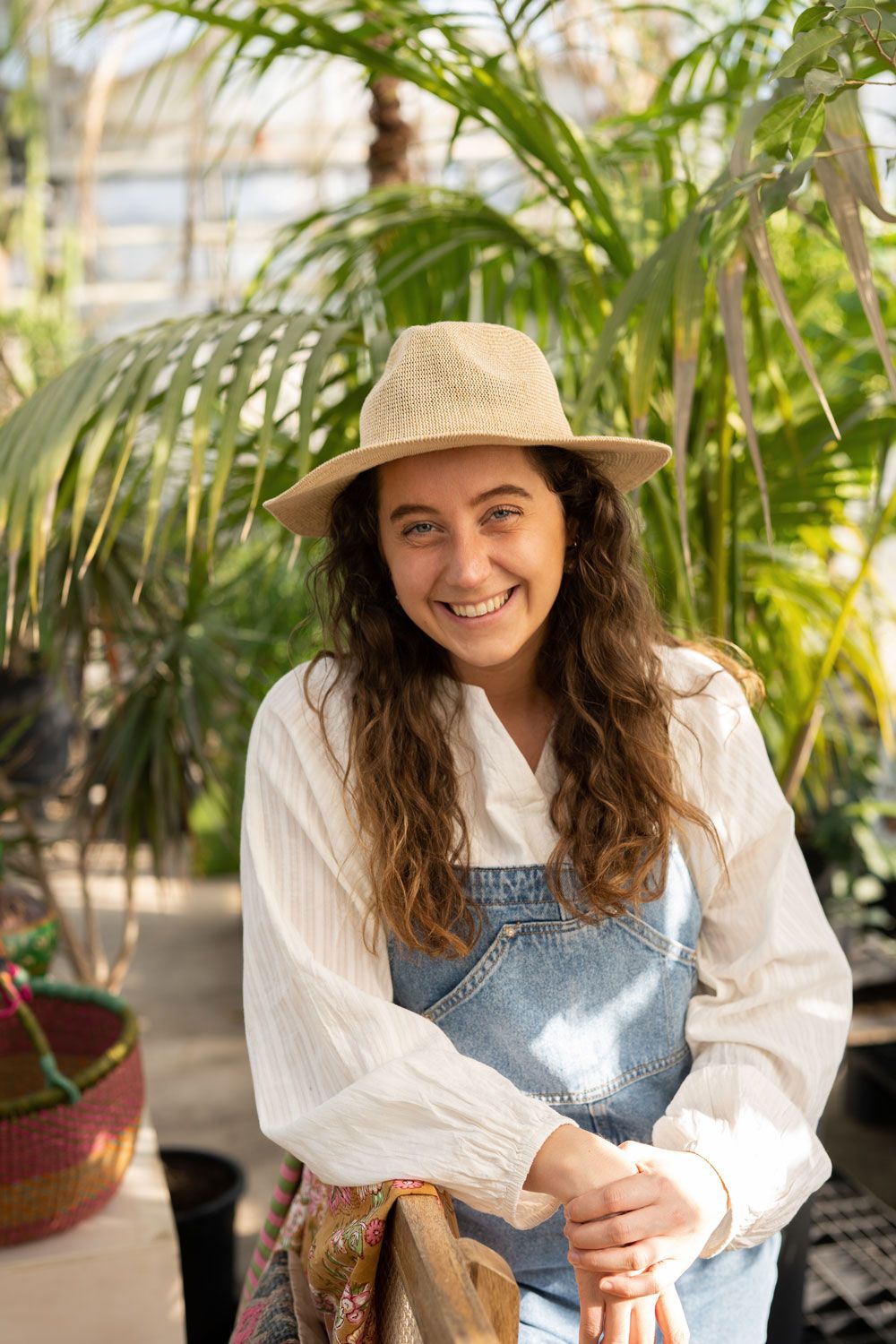 Stylist Lotte met hoed en tuinpak lacht naar de camera