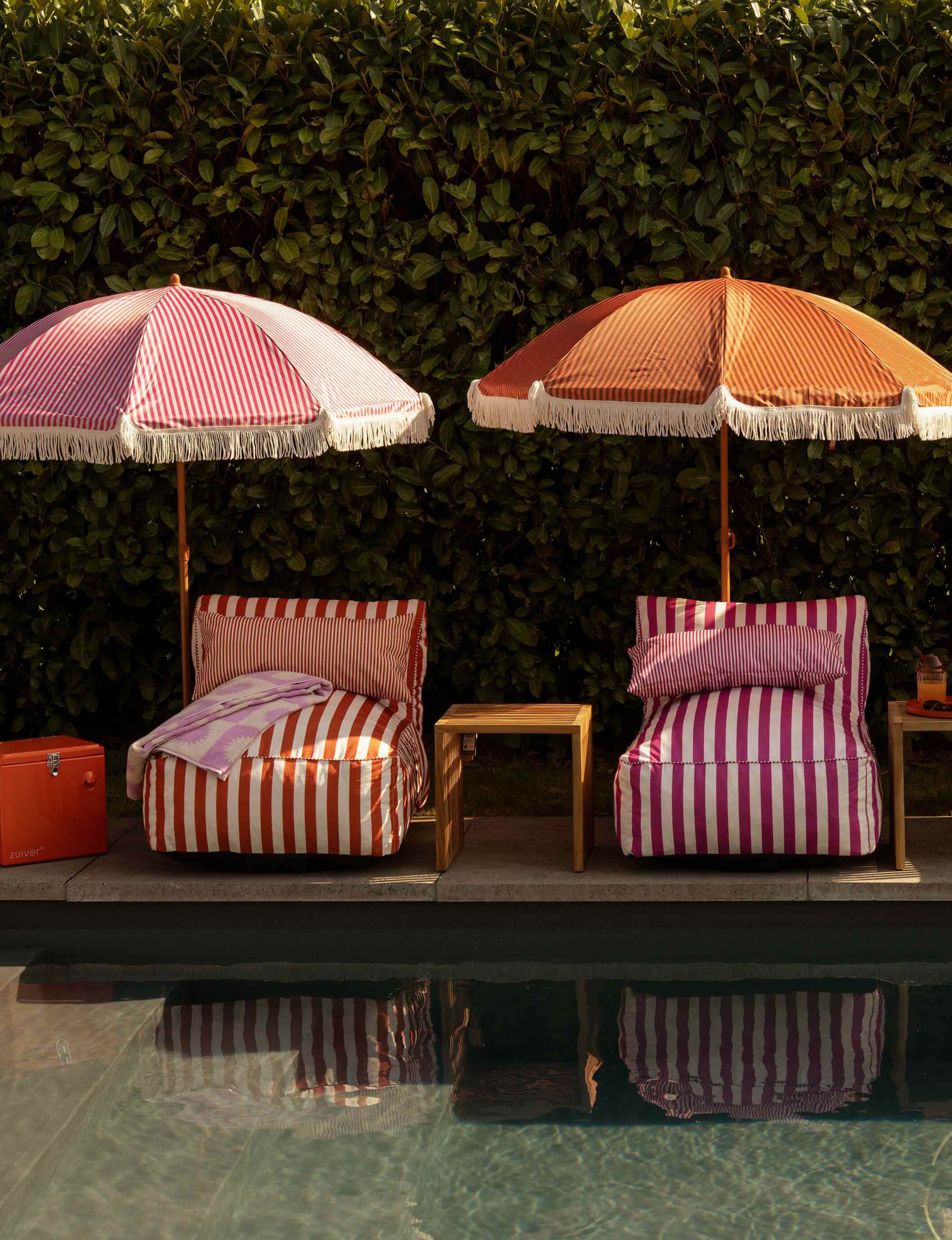 Gestreepte zonnebedjes en parasols langs het zwembad