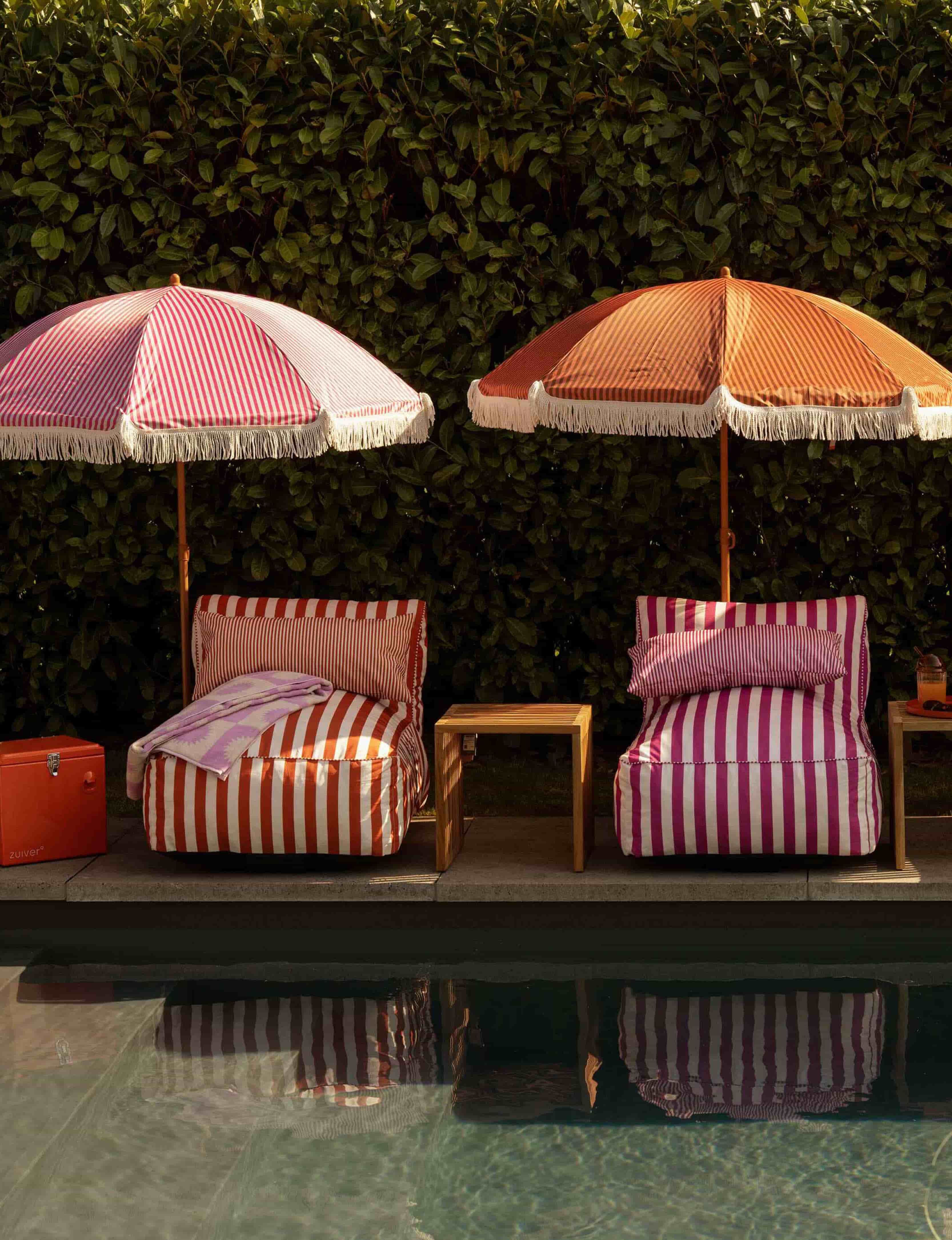 Gestreepte zonnebedjes en parasols langs het zwembad