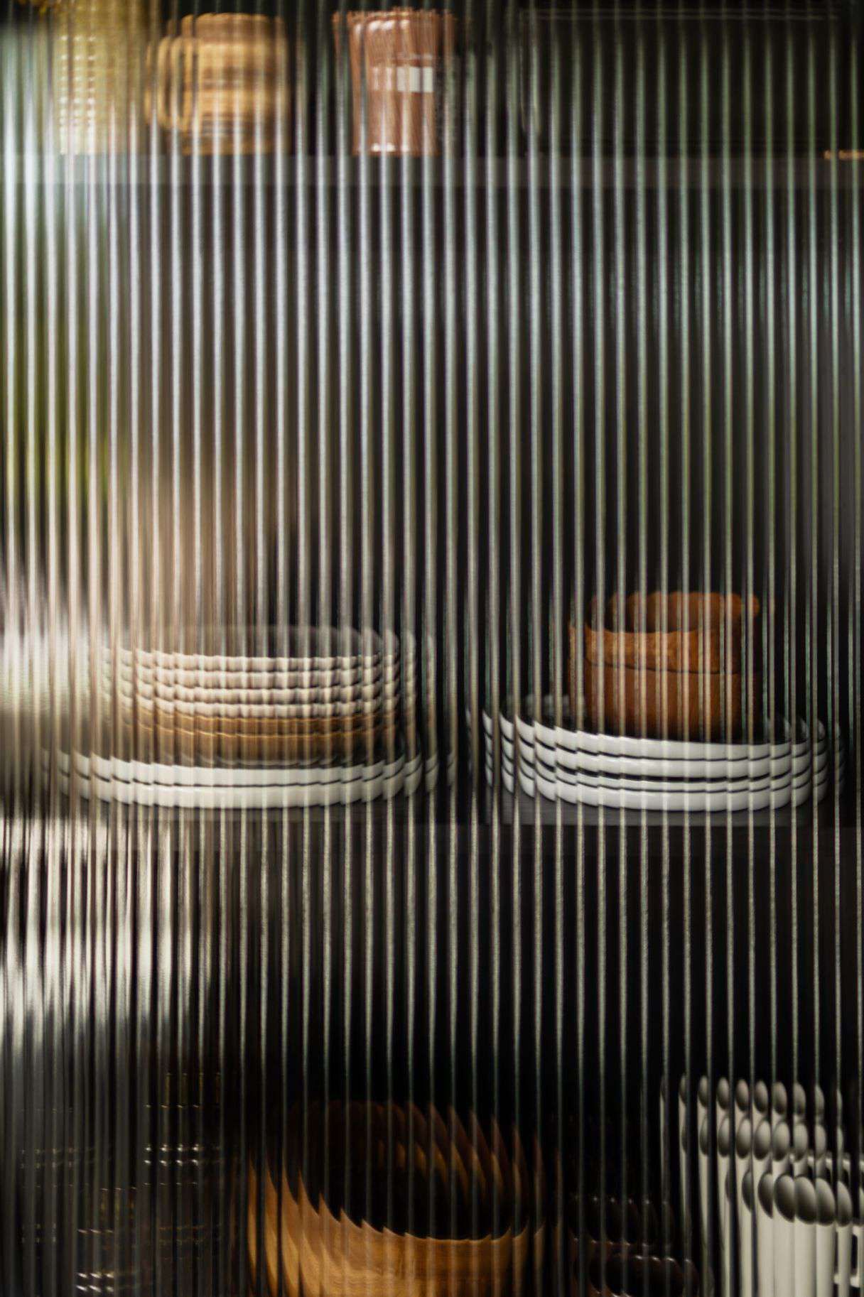 Ribbelglas deur met daarachter servies