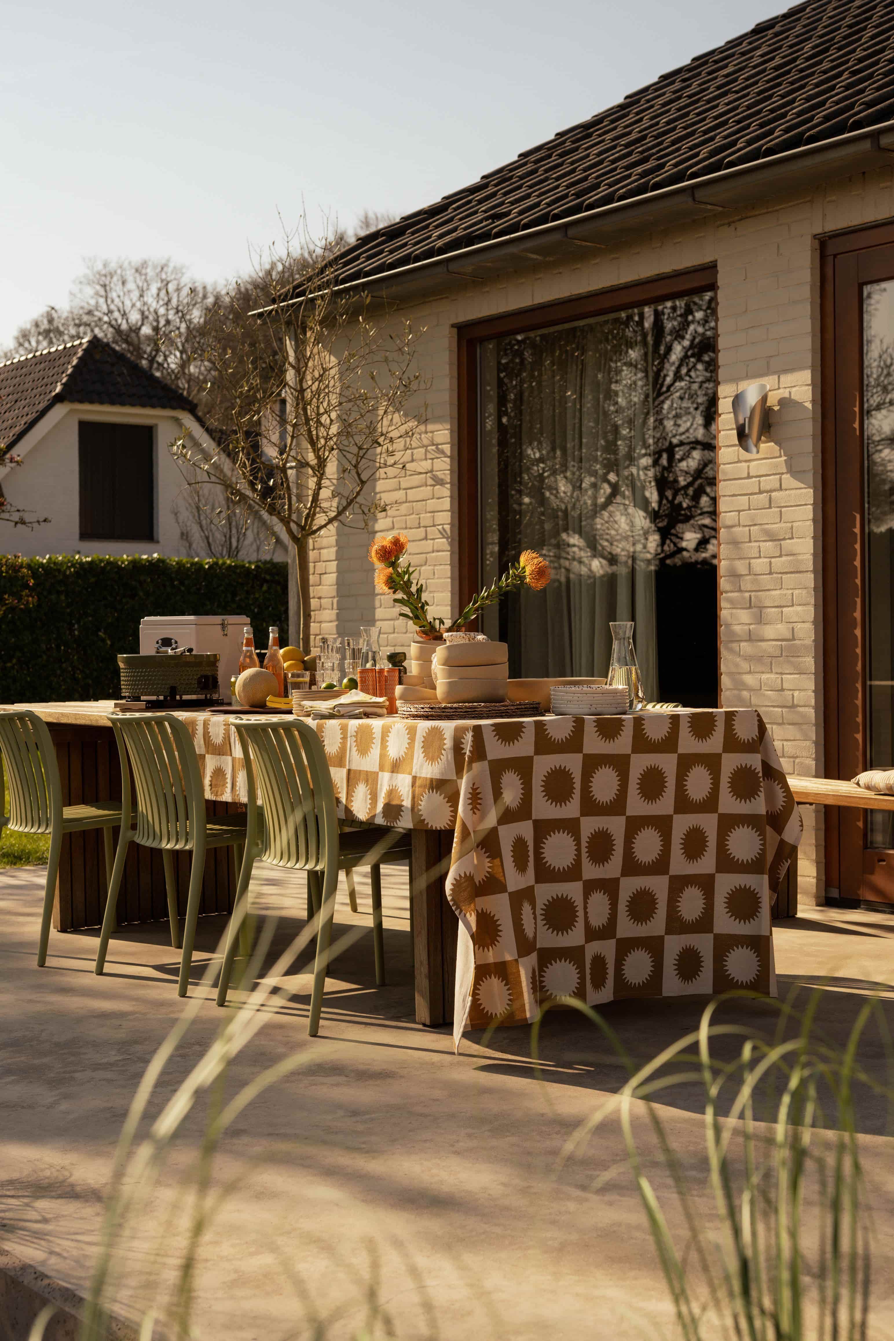 Gedekte tafel in tuin met groene stoelen