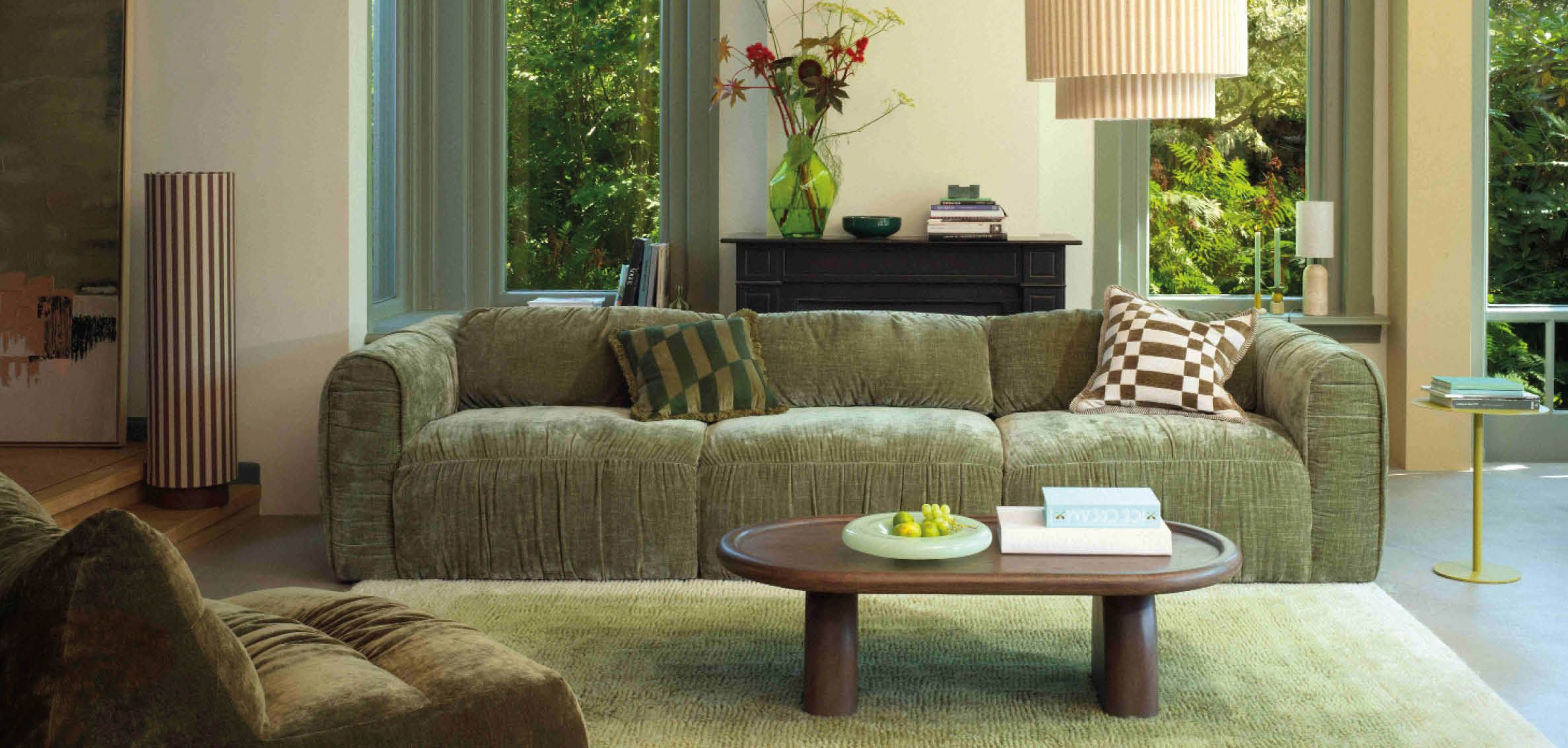 Groene 3-zitsbank in wonkamer met groen kleed en houten salontafel