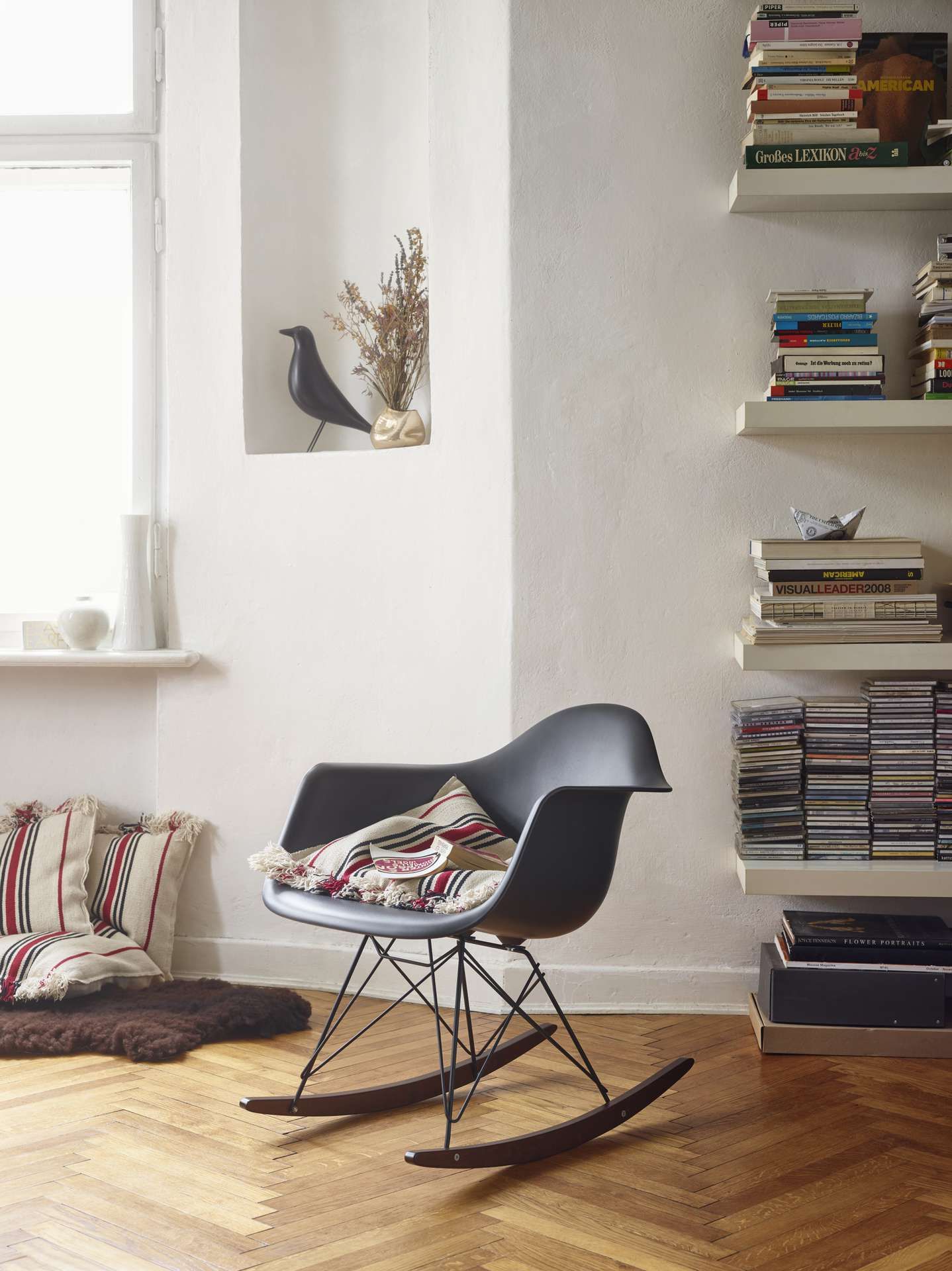 Schommelstoel in grijze kleur van Vitra staat ip houten vloer in kamer