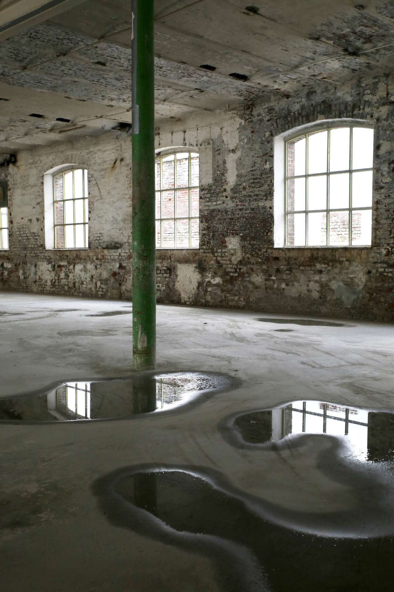 Vloer van lege en oude fabriek met plassen water op de grond
